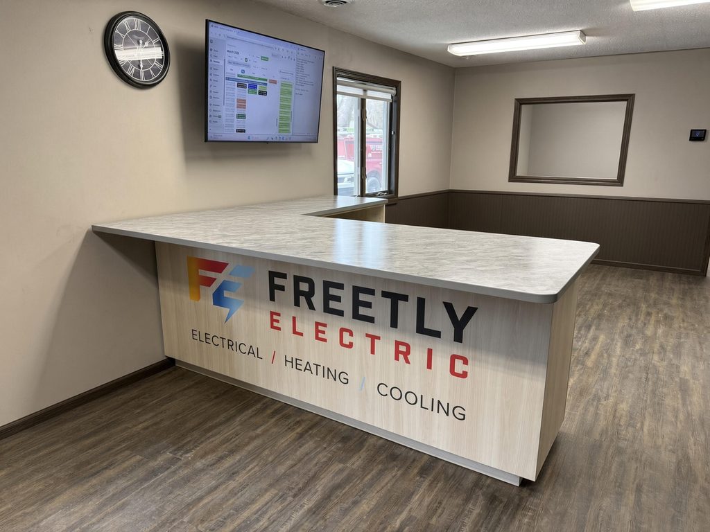 L-shaped reception counter with gray stone-look top and light wood-look front panel with printed company graphics