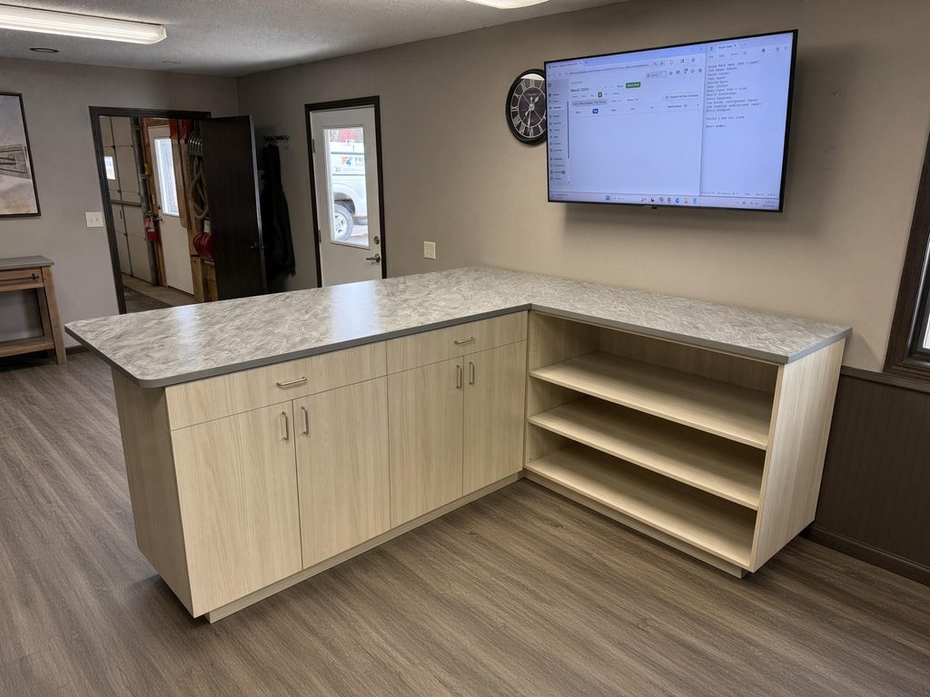 L-shaped light ash-look base cabinets with gray swirl-pattern countertop and open shelving end in a small office